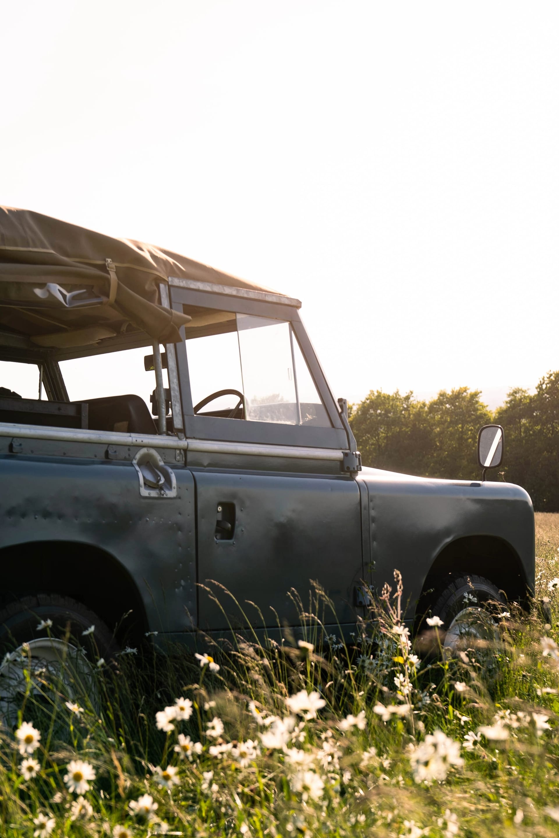 A pastel-green EV Classics converted Series 2A Land Rover — canvas top, slatted grille, round headlamps — three-quarter front view